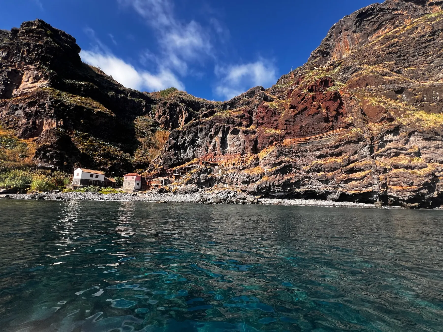 Calhau da Lapa, with its small houses at the foot of the cliffs, seen from the sea